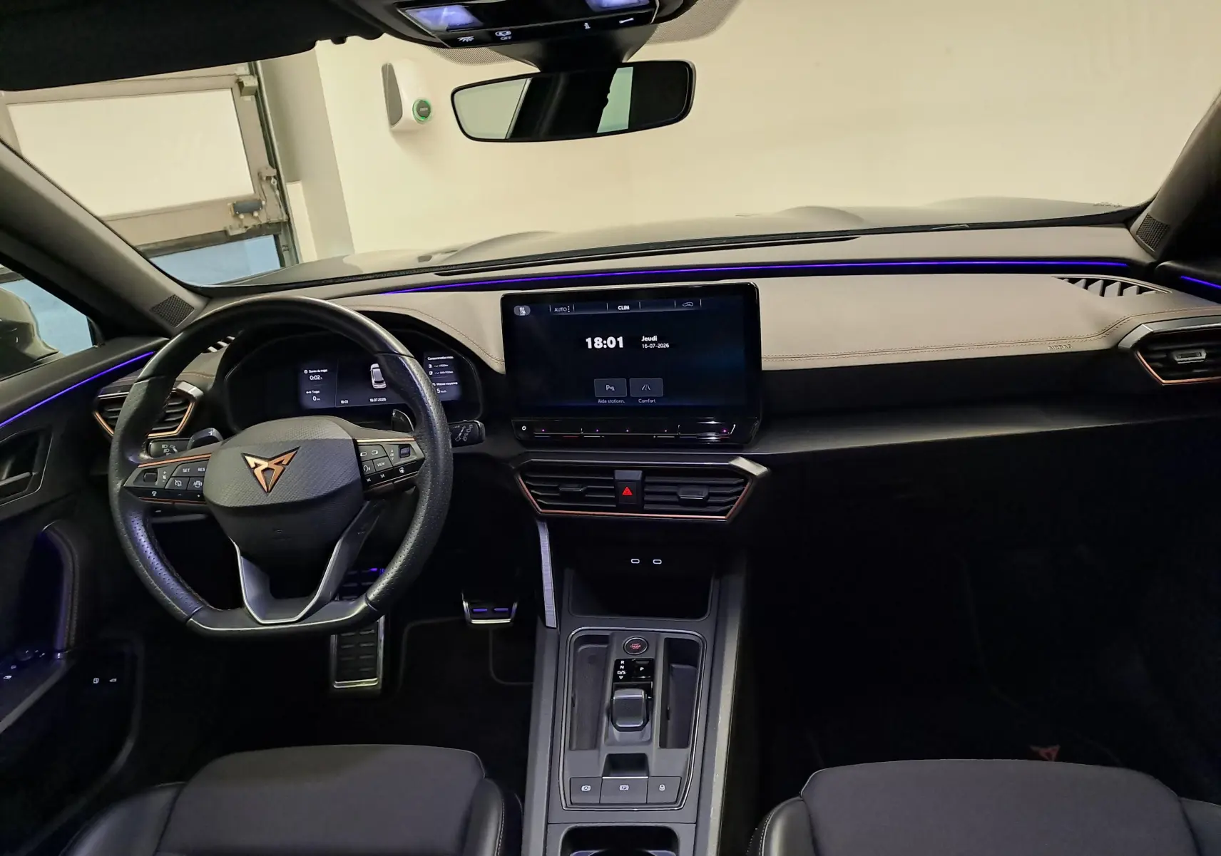 Vue intérieure frontale du CUPRA Formentor 1.4 e-HYBRID 245 DSG6 VZ avec tableau de bord clair et éclairage d’ambiance violet.