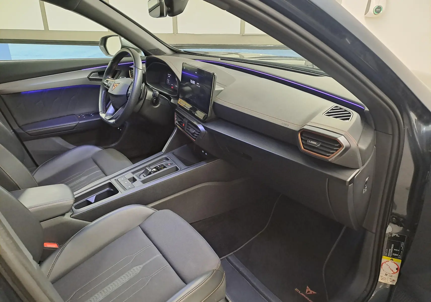 Vue intérieure côté conducteur du CUPRA Formentor 1.4 e-HYBRID 245 DSG6 VZ 2024 avec éclairage d'ambiance violet et finitions noires.