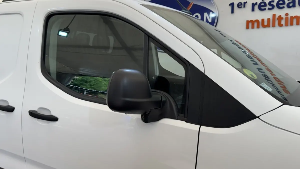 Vue latérale gauche rapprochée du Peugeot Partner blanc, mettant en valeur la porte et le rétroviseur noir.