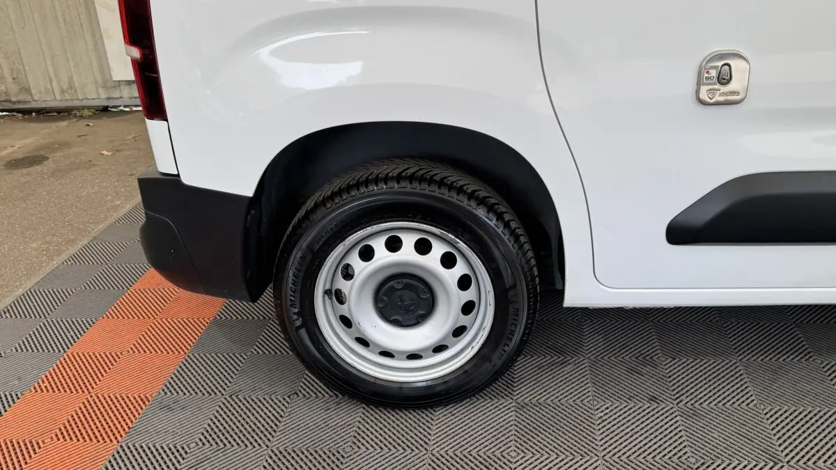 Gros plan sur la roue arrière droite blanche d’un Peugeot Partner 2021 avec jante acier et carrosserie blanche.