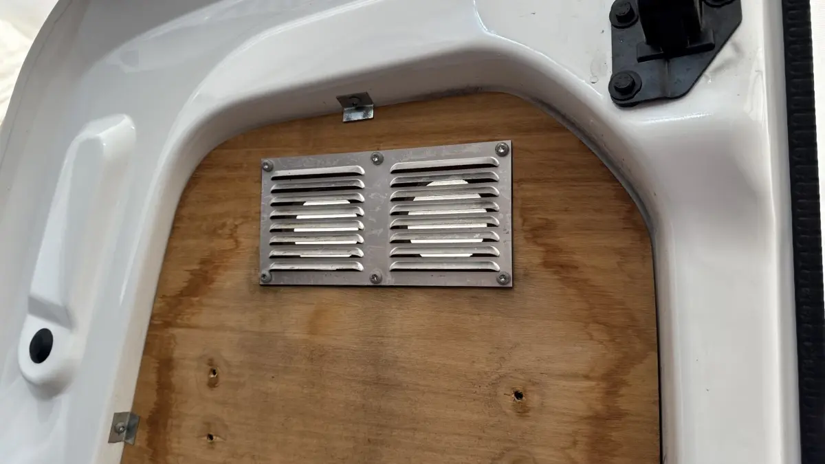 Gros plan sur la cloison en bois avec grille d’aération du Peugeot Partner blanc, vue intérieure arrière.