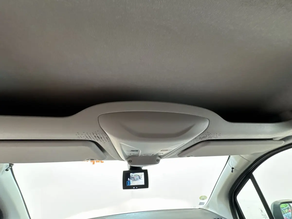 Vue intérieure avant du Peugeot Partner blanc, avec écran de caméra de recul suspendu au plafond.