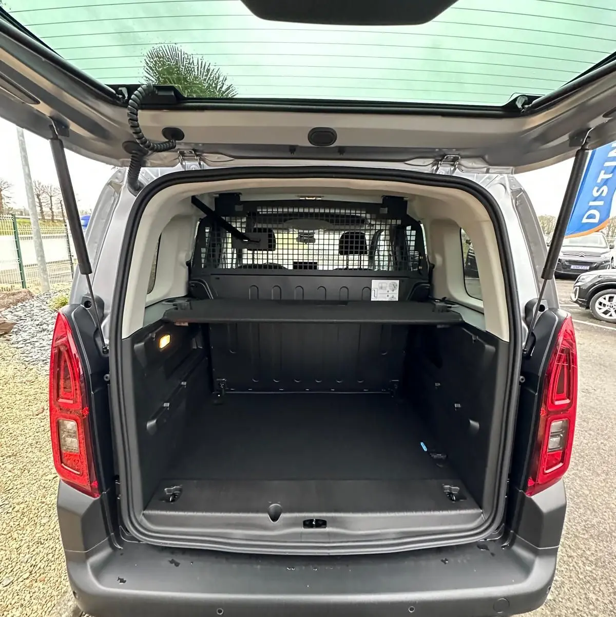 Vue arrière ouverte du Citroën Berlingo gris Artense 2025, montrant l’espace de chargement et la grille de séparation intérieure.