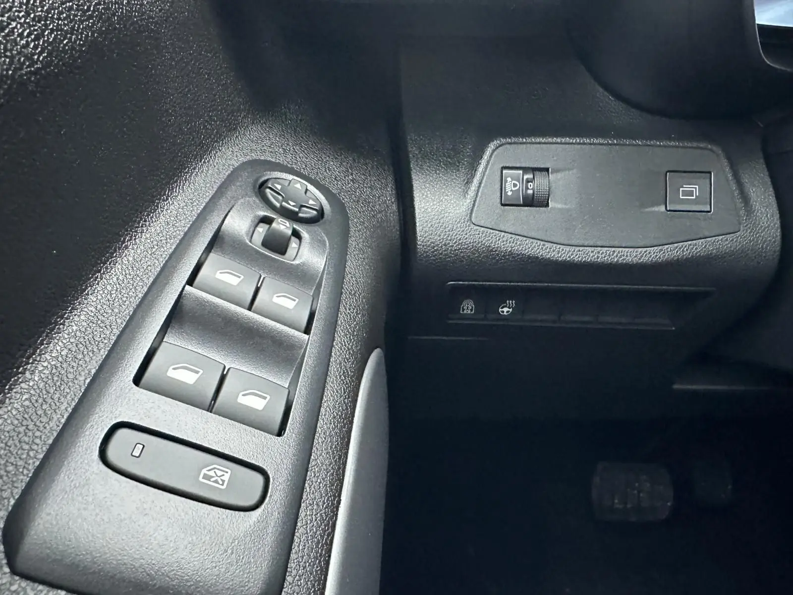 Gros plan sur les commandes de lève-vitres et réglage des rétroviseurs côté conducteur du Citroën Berlingo gris Artense 2025.