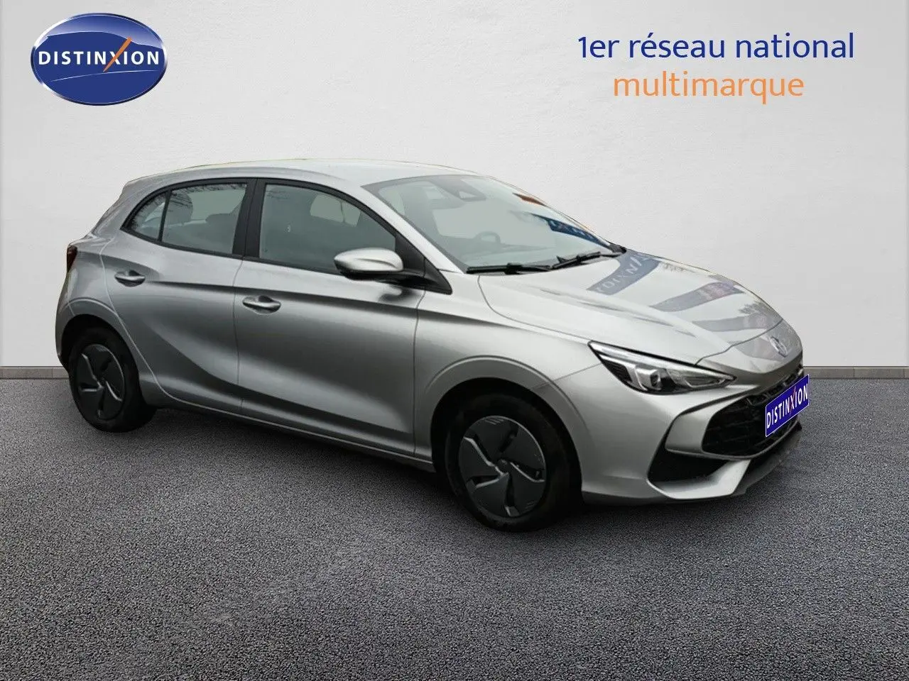 Vue 3/4 avant droite d'une MG3 Hybrid+ gris métallisé avec jantes en acier et enjoliveurs noirs, stationnée sur sol gris.