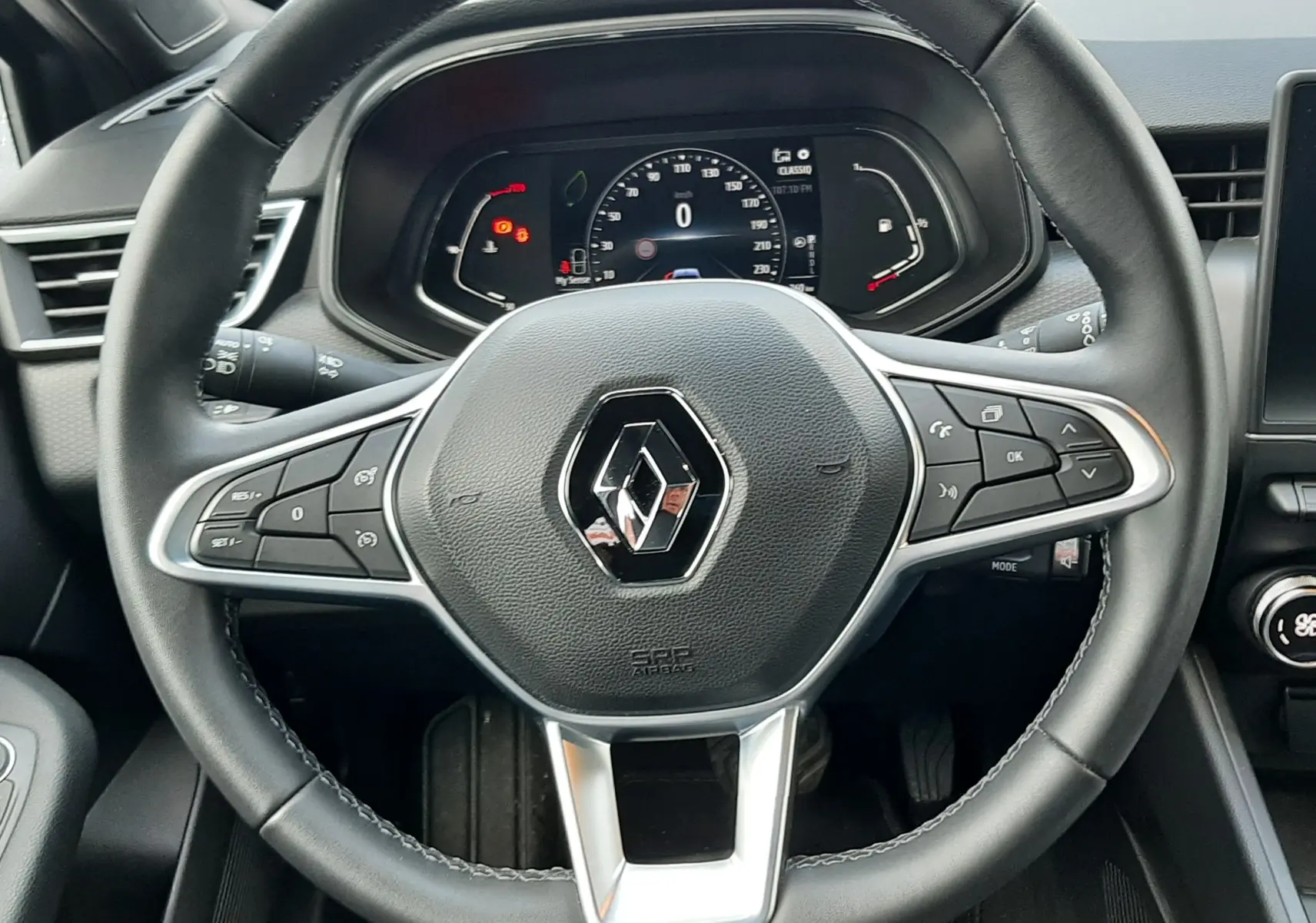 Vue centrée sur le volant noir du Renault Clio V TCE 90 Intens avec tableau de bord digital allumé.