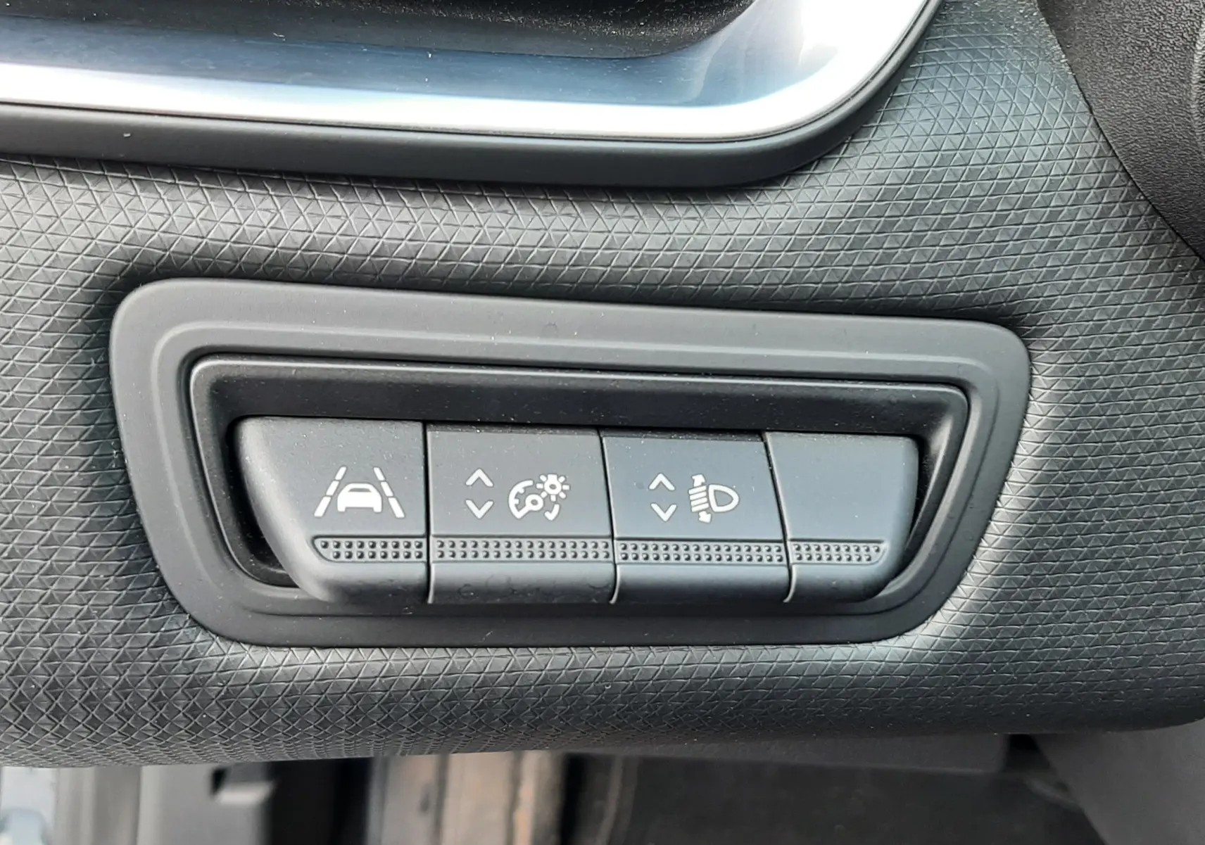 Gros plan sur les commandes de réglage d'assistance et d'éclairage dans l'habitacle d'une Renault Clio V gris titanium.