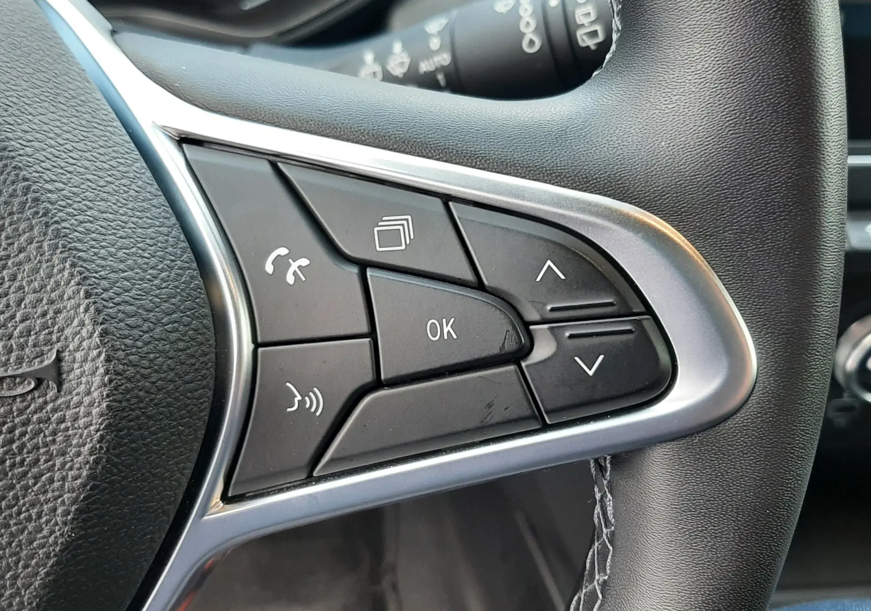 Gros plan sur les commandes multifonctions côté droit du volant cuir de la Renault Clio V gris titanium 2021.