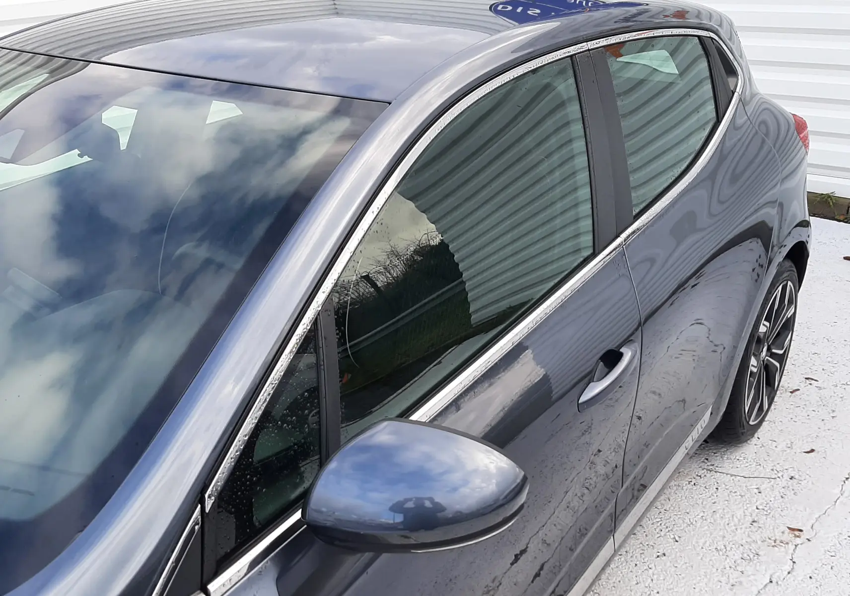 Vue 3/4 arrière côté gauche d'une Renault Clio V gris titanium avec jantes alliage et vitres teintées.