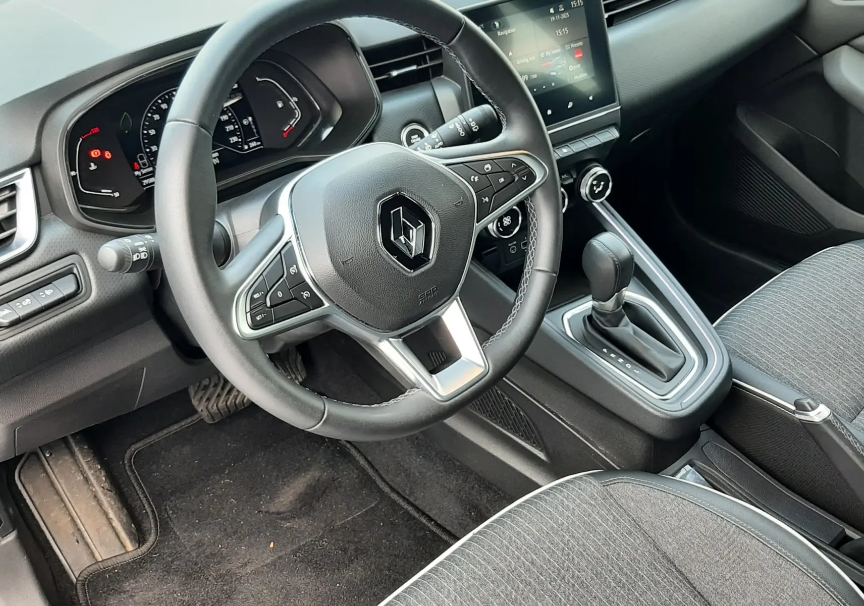 Vue intérieure côté conducteur de la Renault Clio V TCE 90 Intens avec volant multifonction et console centrale moderne.