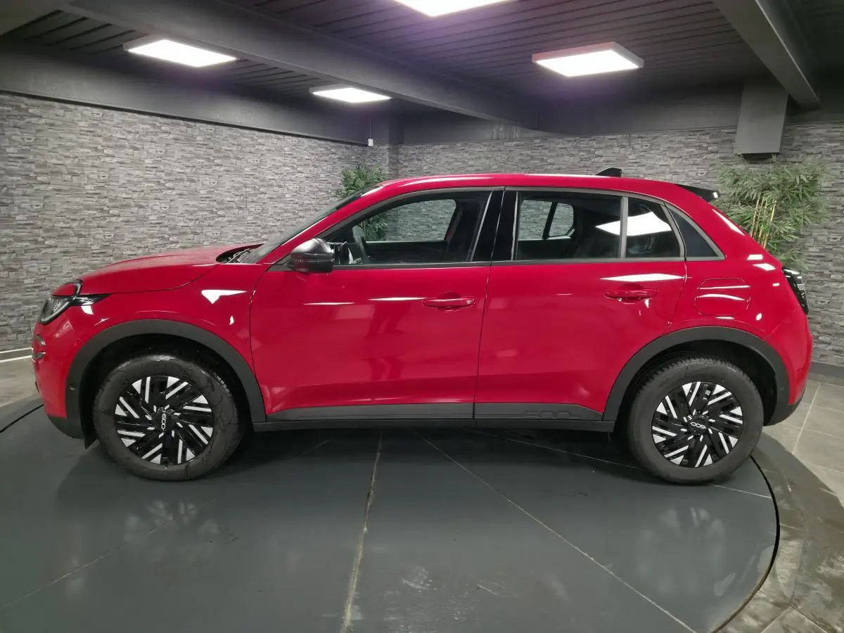 Profil côté gauche d'une FIAT 600 1.2 Hybrid rouge vif avec jantes 16'' bicolores et coques de rétroviseurs noires.