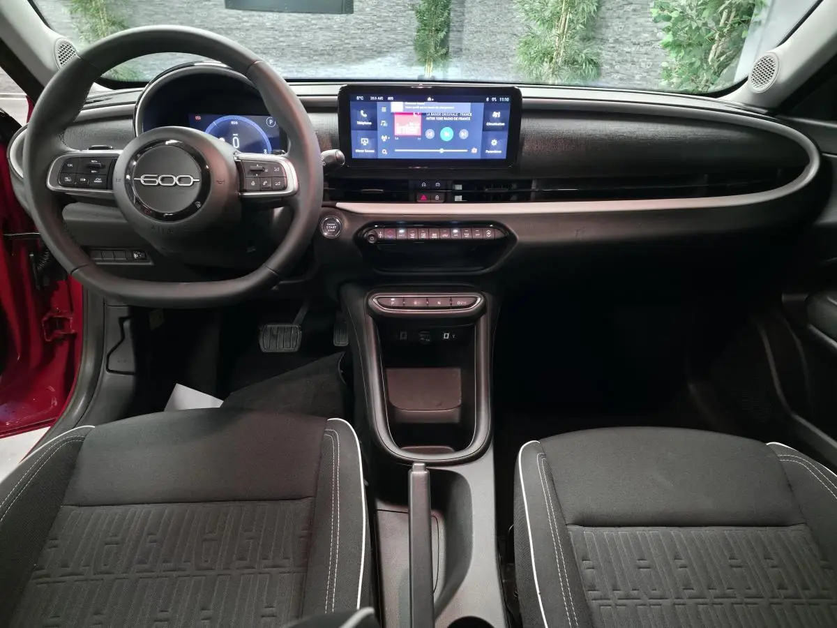 Intérieur noir de la FIAT 600 2024, vue avant du tableau de bord avec écran tactile et volant 600 central.
