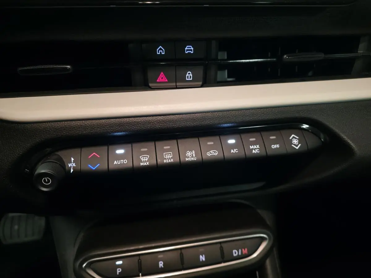 Vue rapprochée de la console centrale de la Fiat 600 rouge 2024, montrant les commandes de climatisation et la boîte auto.