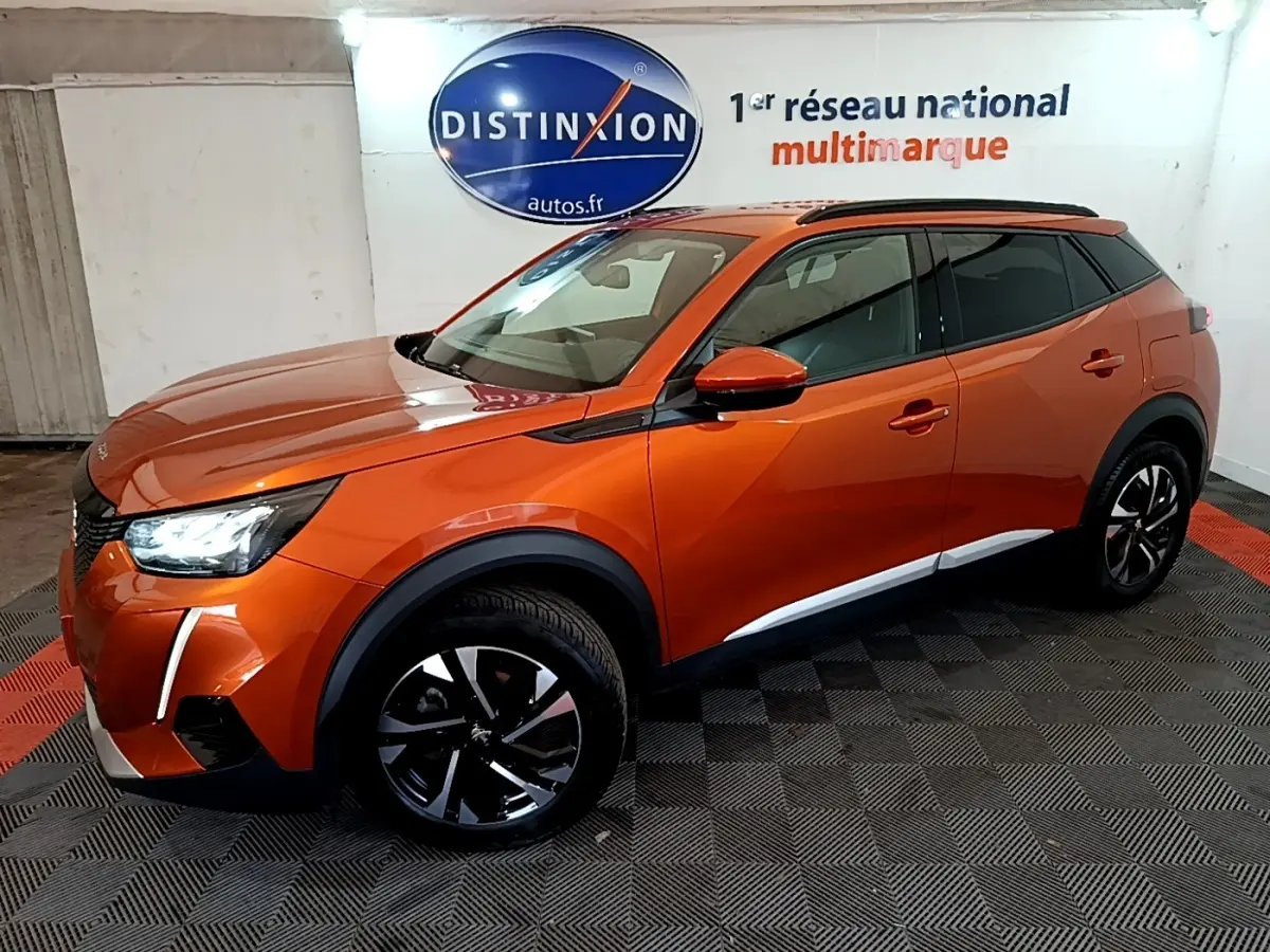 Peugeot 2008 orange vue 3/4 avant droit dans un showroom avec jantes noires et toit noir.