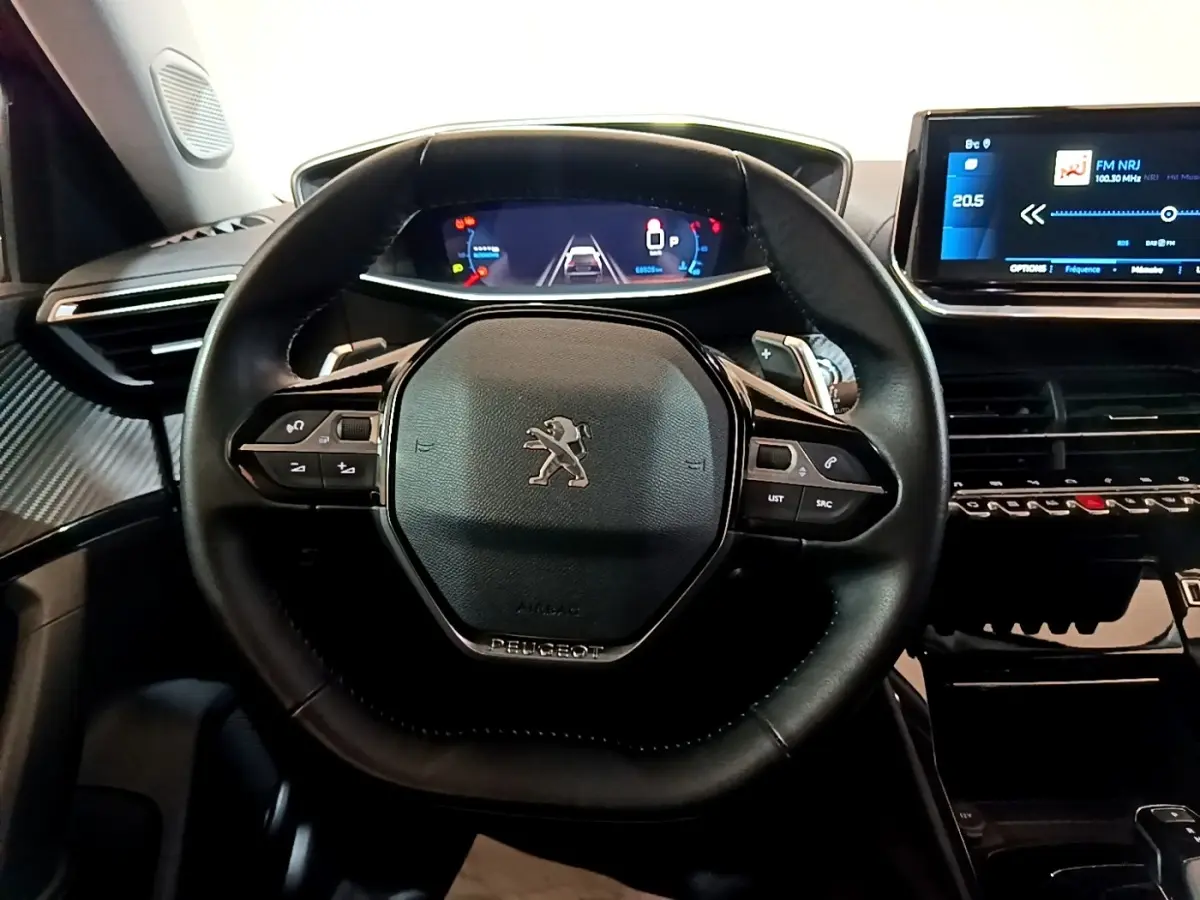 Vue centrée sur le volant cuir noir du Peugeot 2008 2021, avec tableau de bord numérique et écran tactile visible.