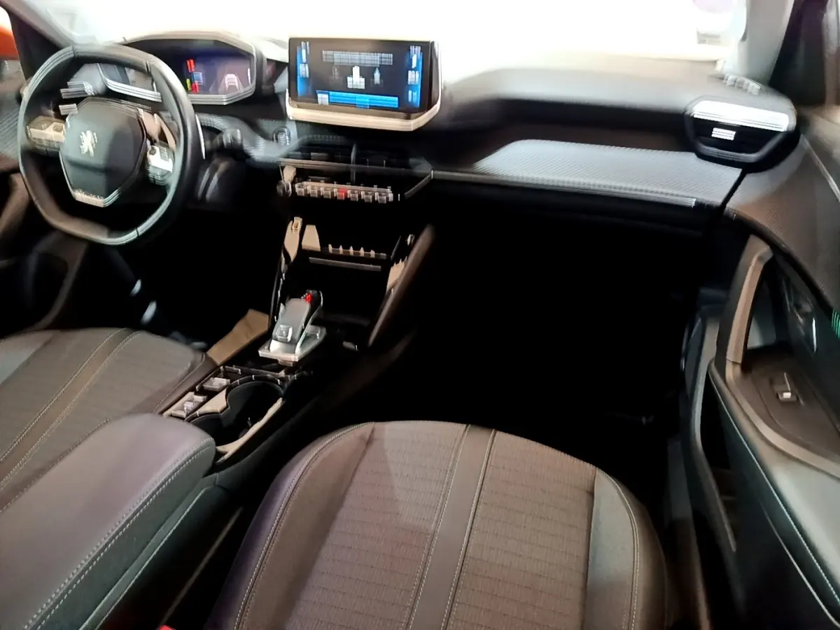 Vue intérieure avant droite du Peugeot 2008, tableau de bord moderne avec écran tactile et volant multifonctions noir.
