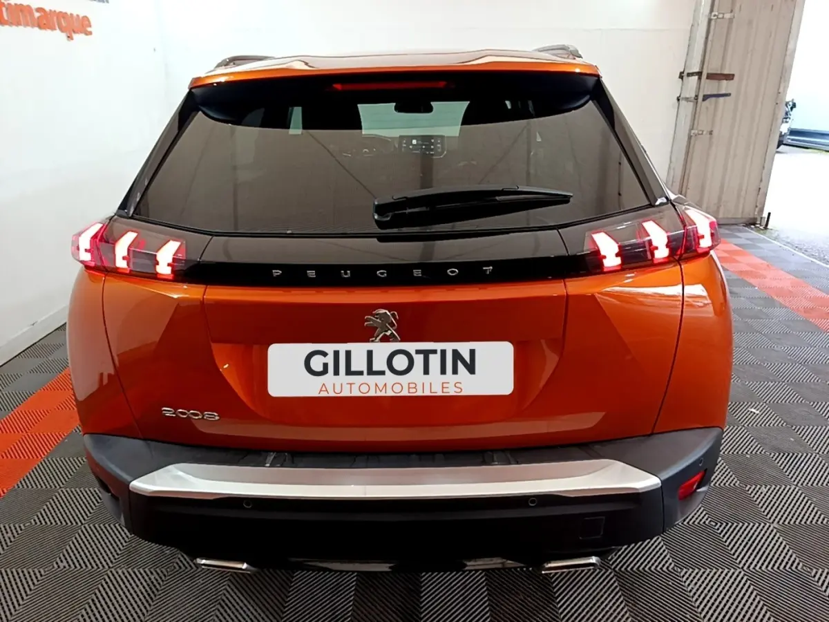 Vue arrière d'un Peugeot 2008 orange avec feux arrière LED caractéristiques et logo central sur hayon noir.