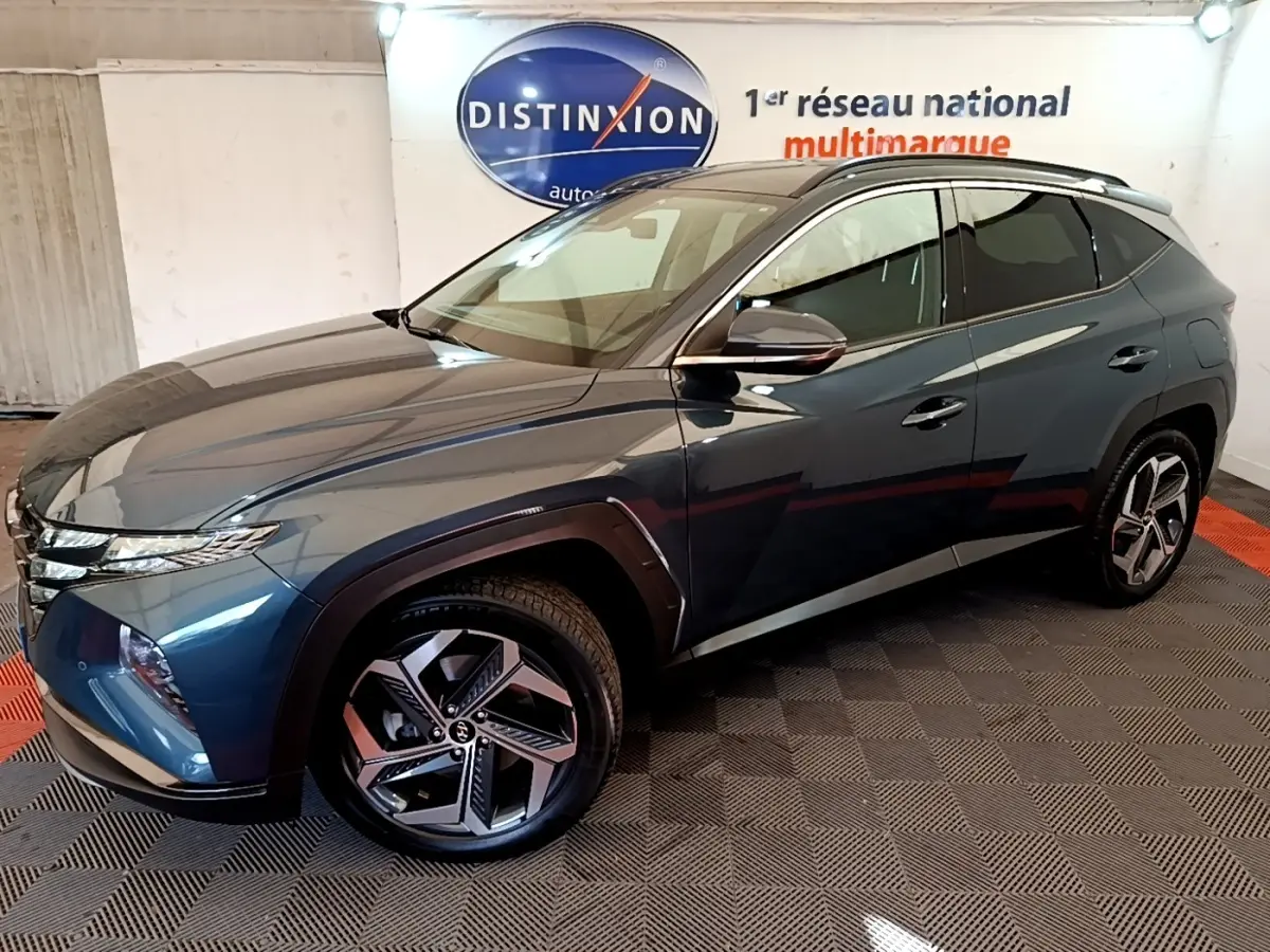 Vue 3/4 avant droit du Hyundai Tucson bleu 2023 avec jantes alliage et toit noir dans un showroom.