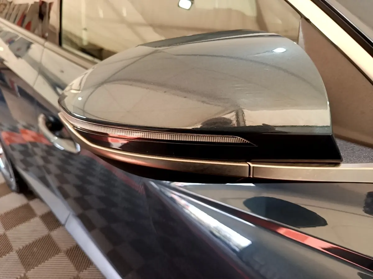 Gros plan sur le rétroviseur côté conducteur bleu du Hyundai Tucson 2023, avec clignotant intégré noir brillant.