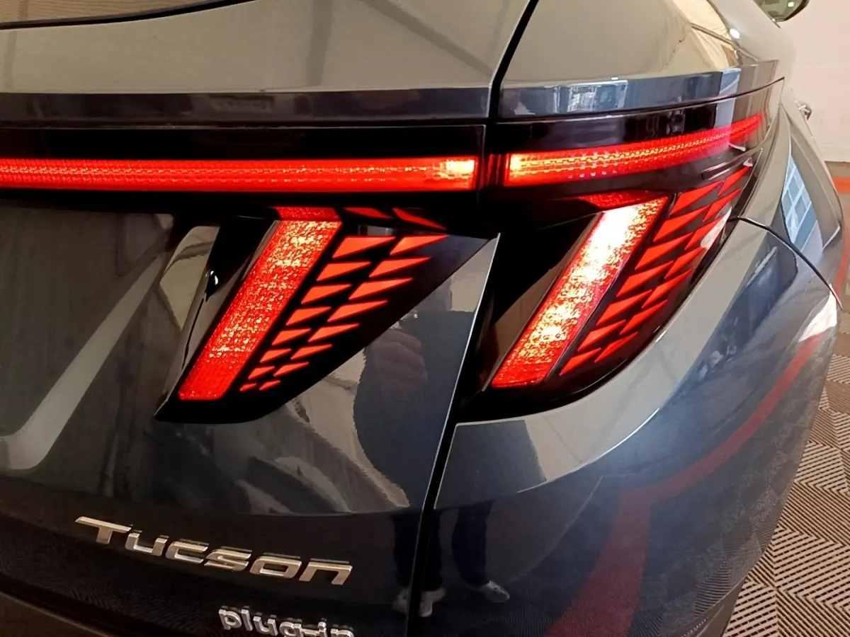Gros plan sur le feu arrière droit allumé du Hyundai Tucson bleu 2023 avec logo Tucson visible sur le hayon.