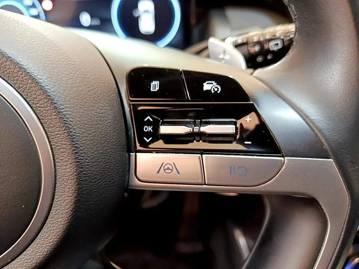 Gros plan sur les commandes multifonctions côté droit du volant cuir du Hyundai Tucson bleu 2023 hybride rechargeable.