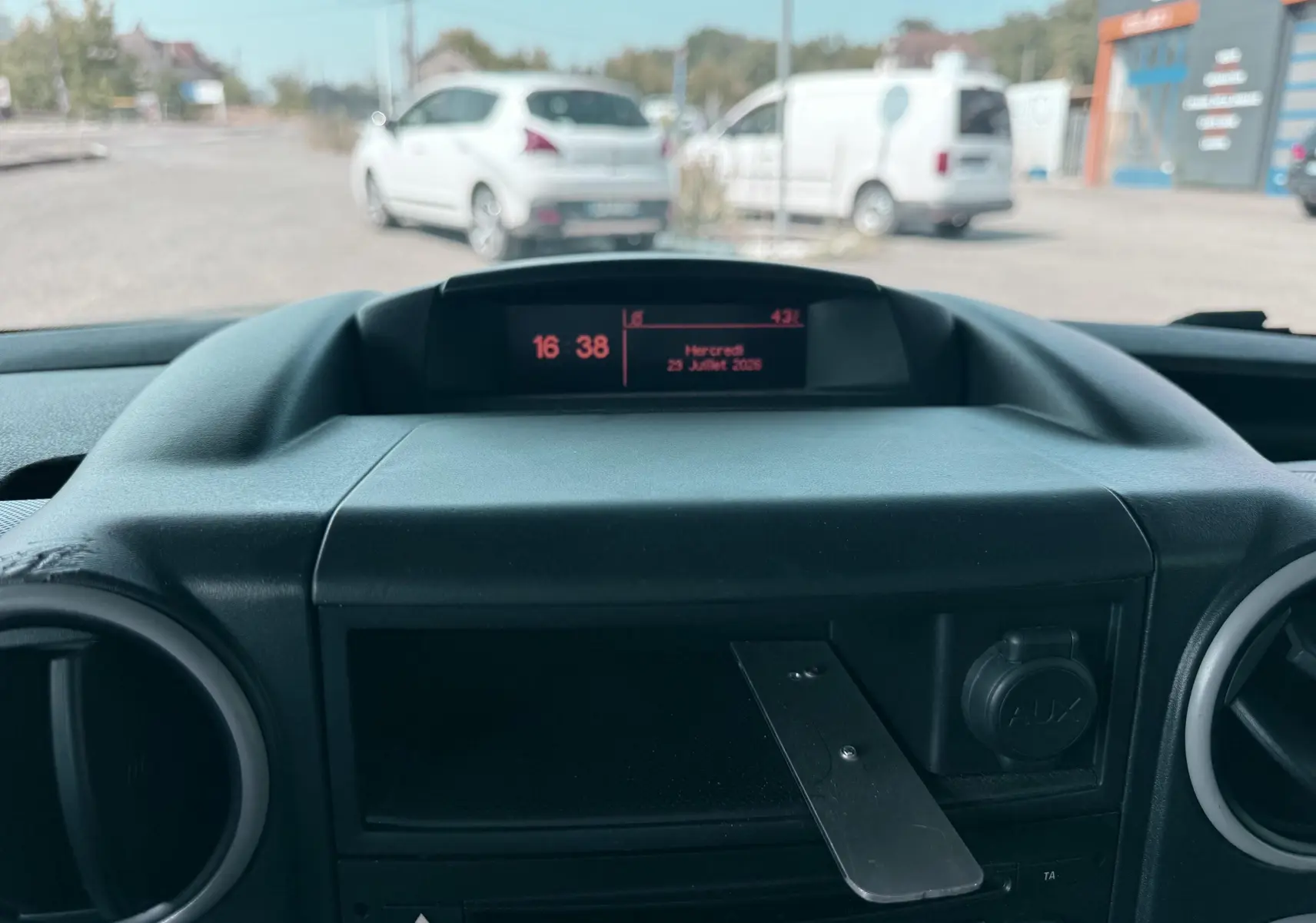 Vue intérieure du tableau de bord du Citroën Berlingo blanc, avec écran central et prise AUX visible.