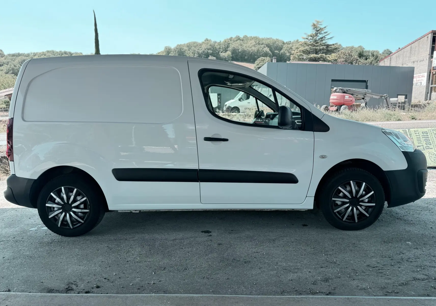Vue de profil côté gauche d'un utilitaire blanc Citroën Berlingo 2016 avec jantes noires et baguettes latérales noires.