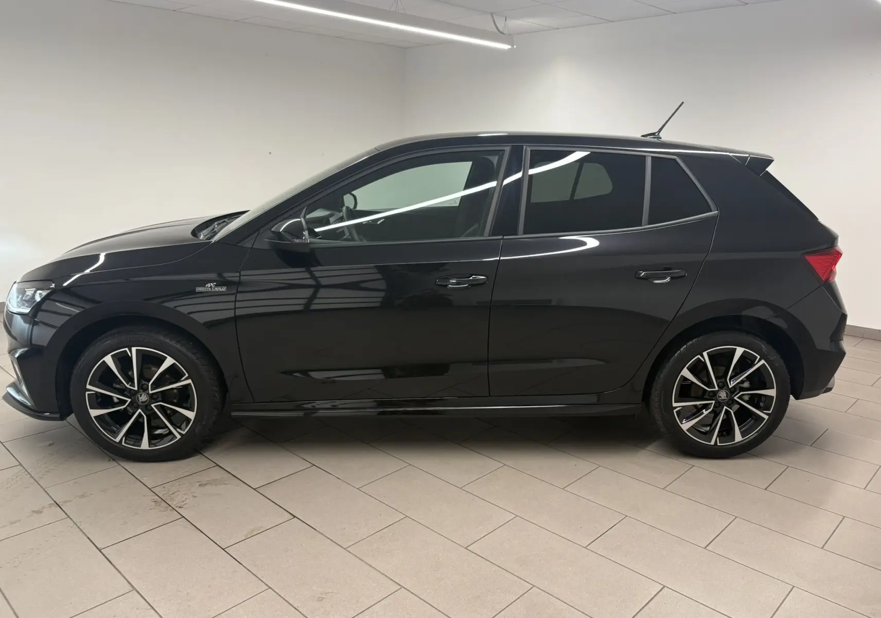 Vue de profil côté gauche d'une Skoda Fabia 2025 noire nacrée Monte Carlo avec jantes alliage et vitres teintées.