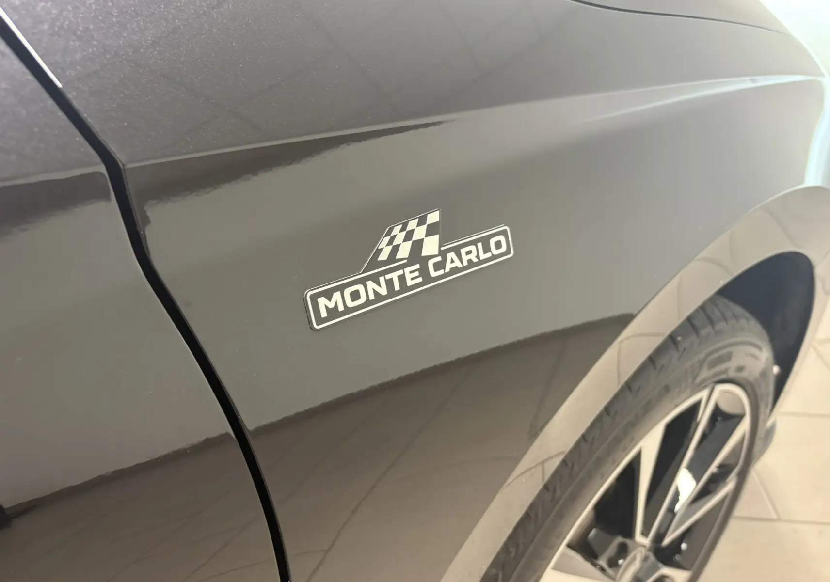 Gros plan sur l’aile avant droite noire nacrée d’une Skoda Fabia Monte Carlo avec logo distinctif et jante alliage visible.