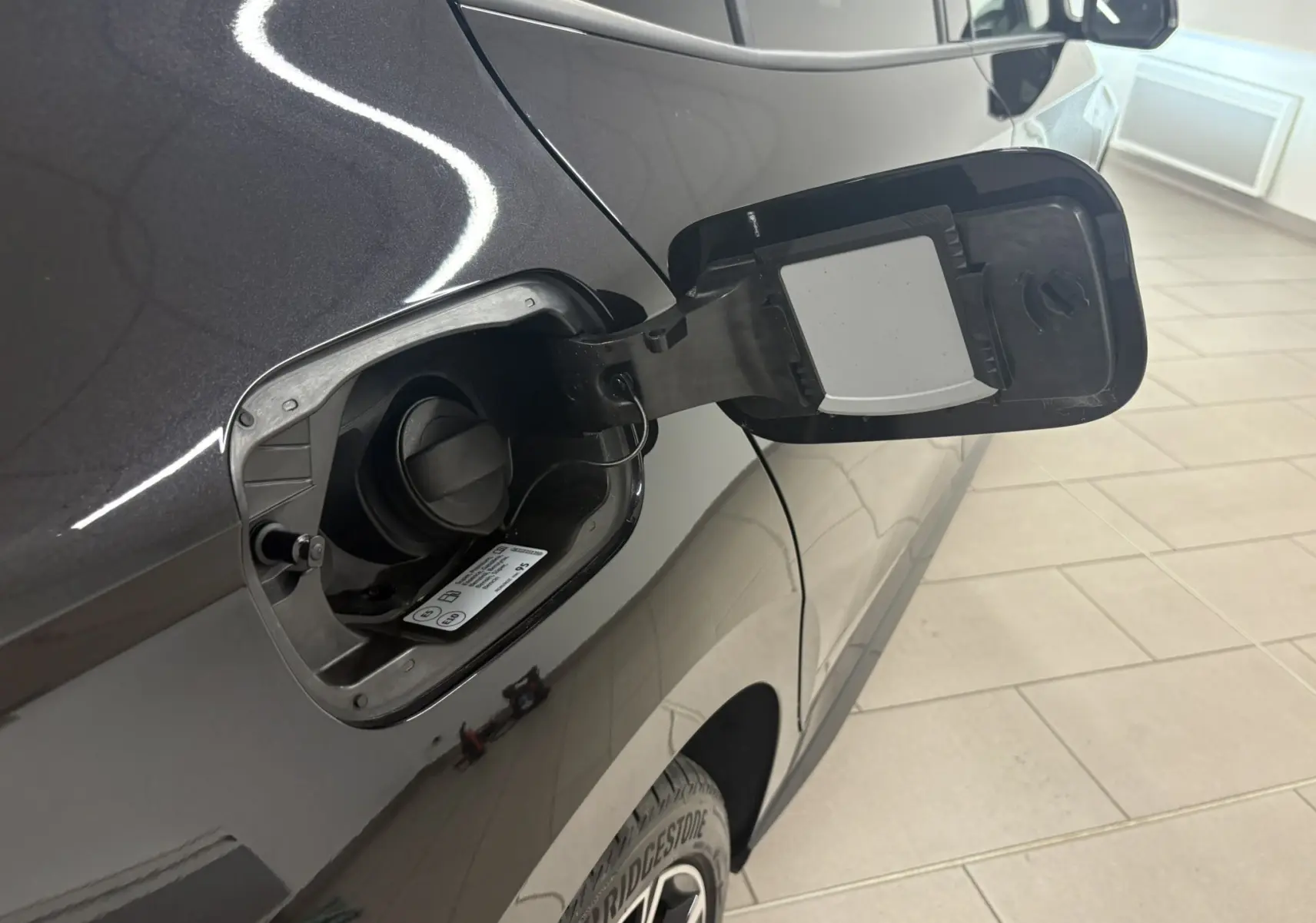 Gros plan sur l'ouverture de la trappe à carburant côté gauche d'une Skoda Fabia 2025 noire nacrée, avec bouchon essence visible.