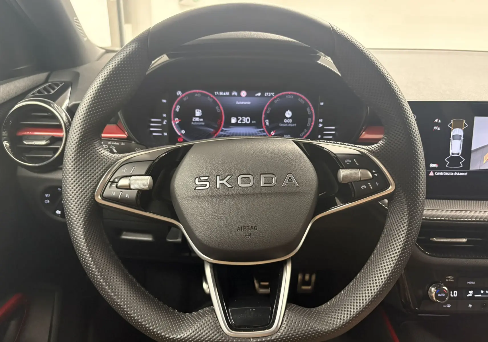 Vue centrée du volant perforé noir de la Skoda Fabia 2025 avec tableau de bord numérique et inserts rouges.