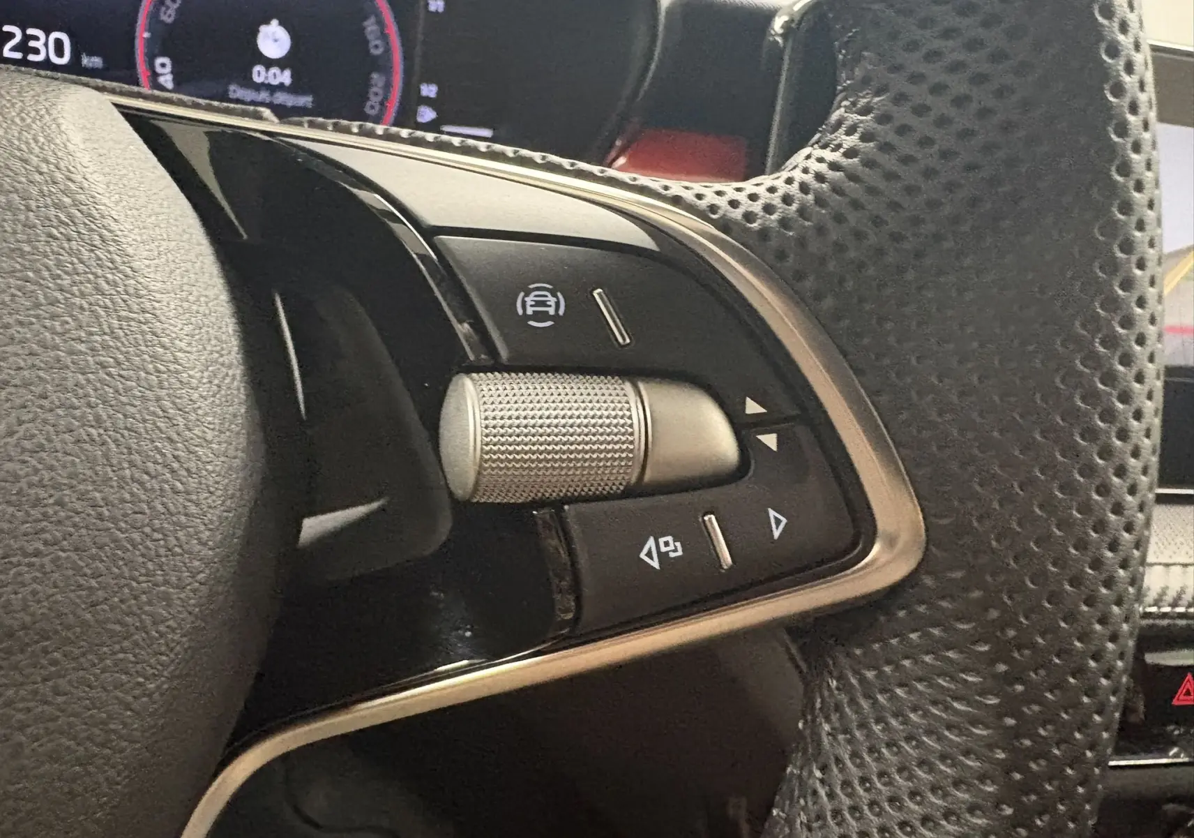 Gros plan sur les commandes gauche du volant perforé de la Skoda Fabia 2025, finition Monte Carlo, avec molette argentée.