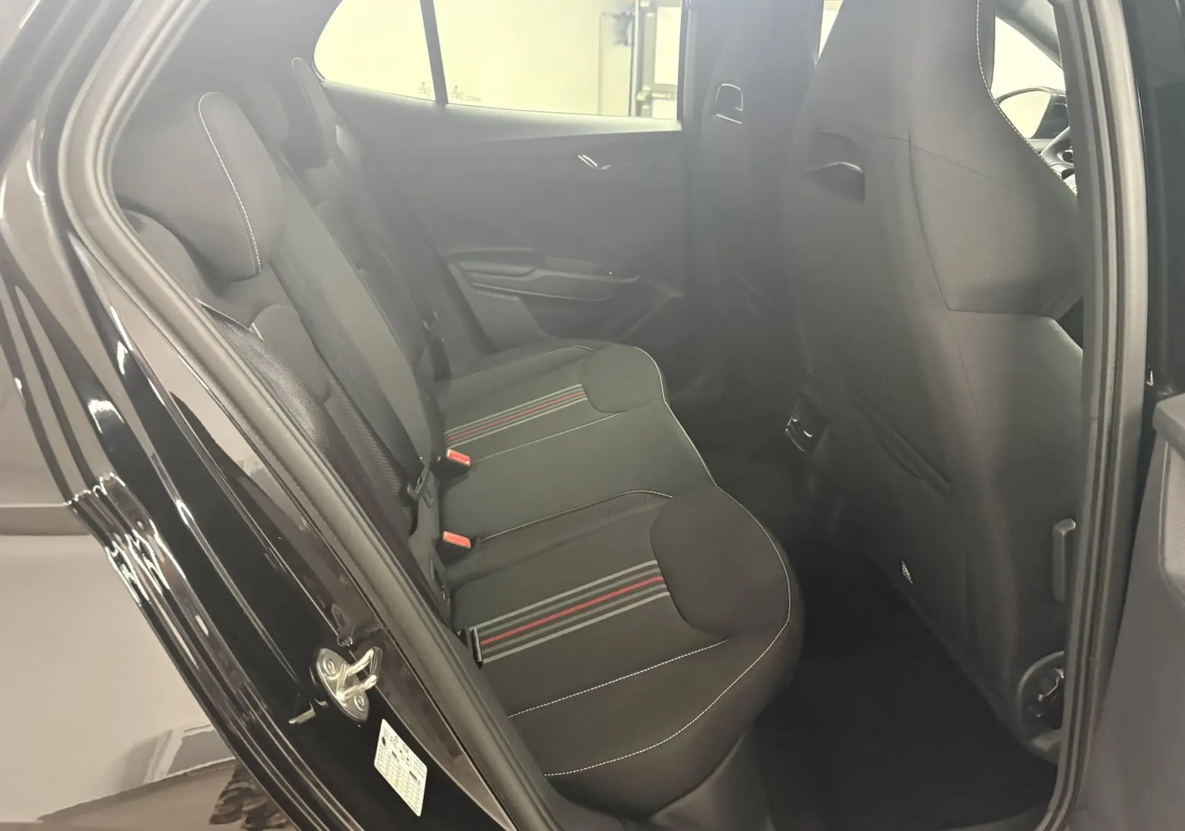Vue intérieure côté gauche des sièges arrière noirs avec surpiqûres blanches et bandes rouges d'une Skoda Fabia 2025 Monte Carlo.