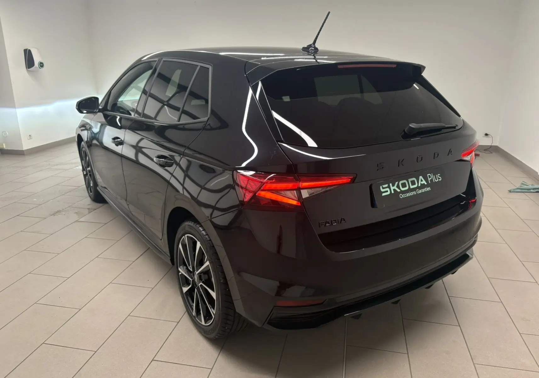 Vue 3/4 arrière droite de la Skoda Fabia 2025 noire nacrée, avec feux allumés et jantes sportives visibles.