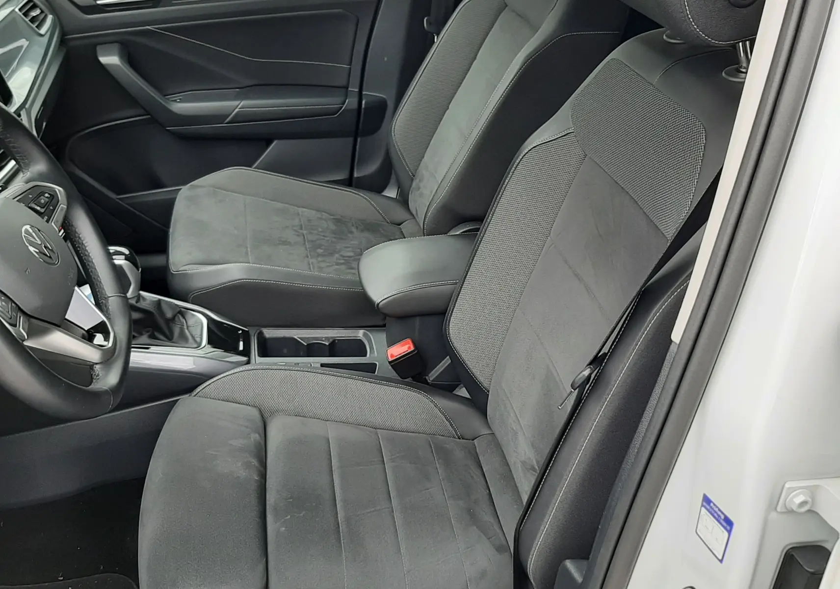 Vue intérieure côté conducteur du Volkswagen T-Roc blanc pur 2022, sièges tissu noir avec accoudoir central.
