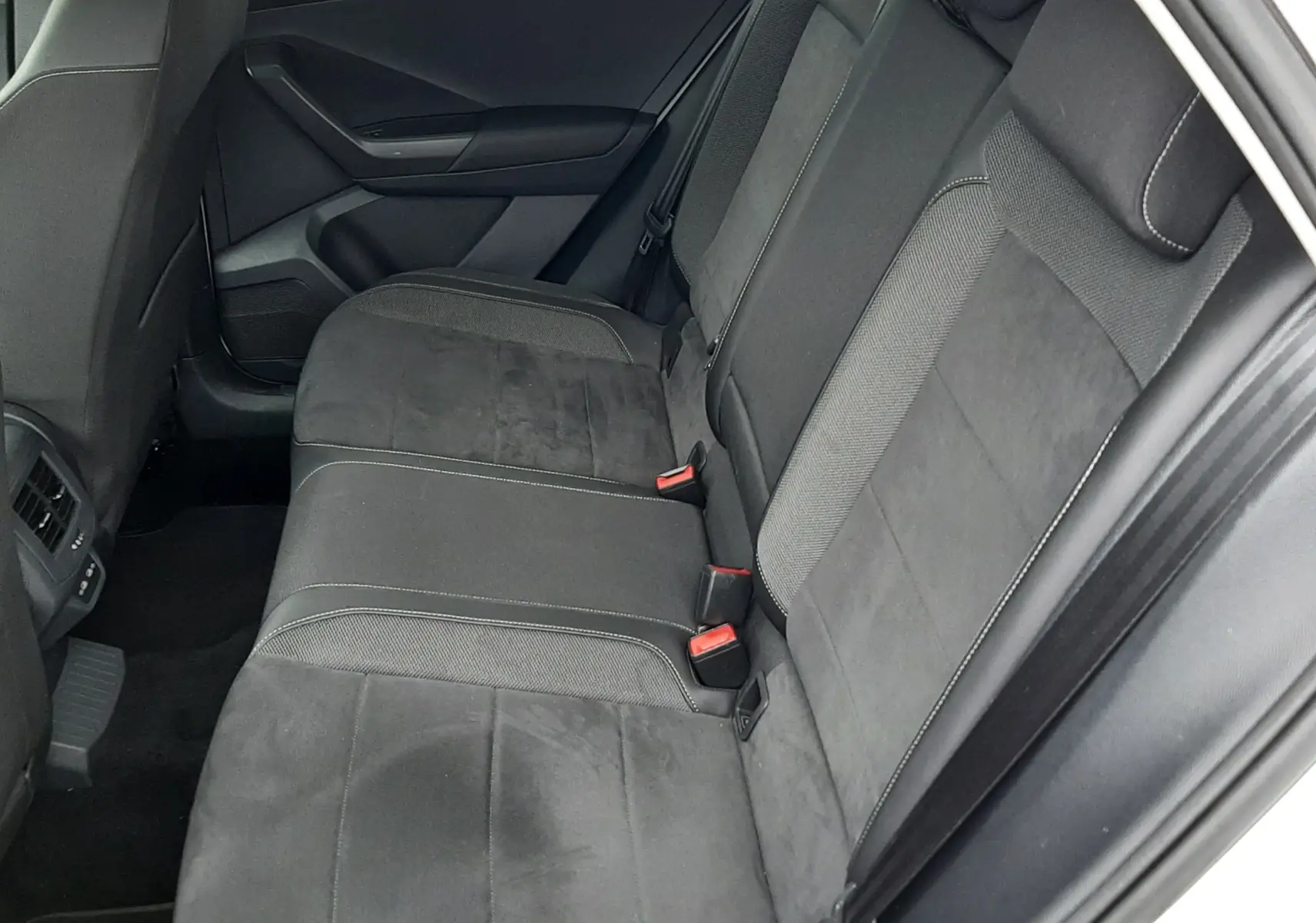 Vue intérieure côté droit des sièges arrière en tissu noir du Volkswagen T-Roc 2022, avec ceinture de sécurité rouge visible.