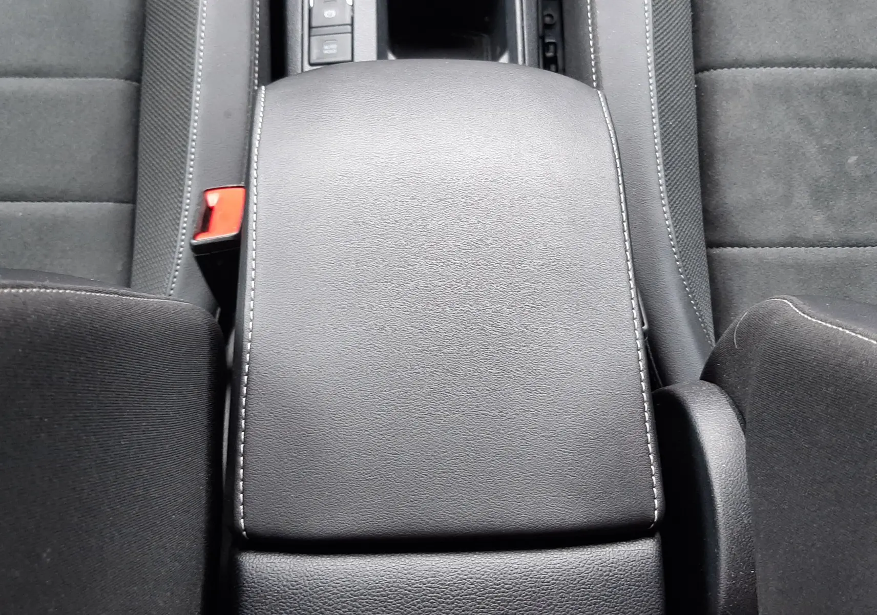 Vue plongeante sur l'accoudoir central noir avec coutures blanches du Volkswagen T-Roc 2.0 TDI 2022, intérieur tissu noir.