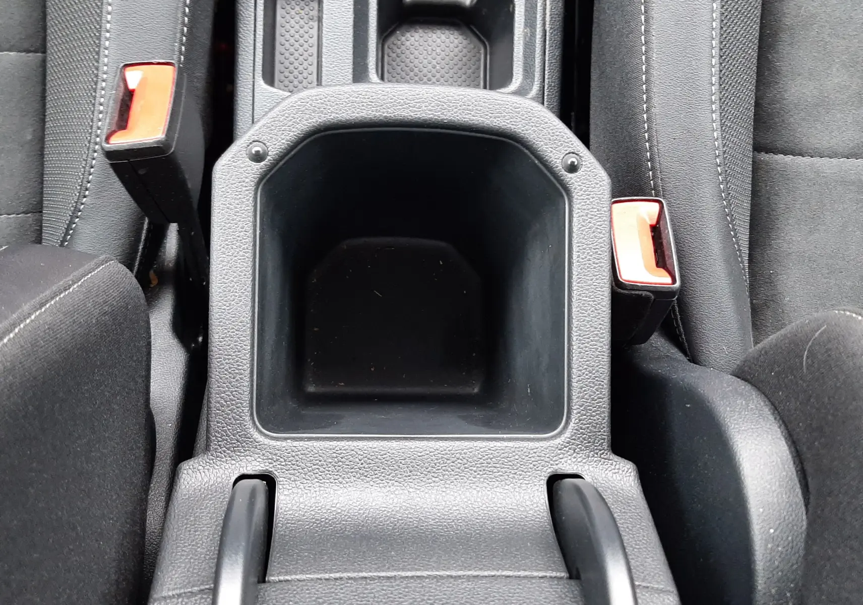 Vue plongeante sur le rangement central noir entre les sièges avant du Volkswagen T-Roc 2.0 TDI 150CH Style DSG7, intérieur tissu noir.