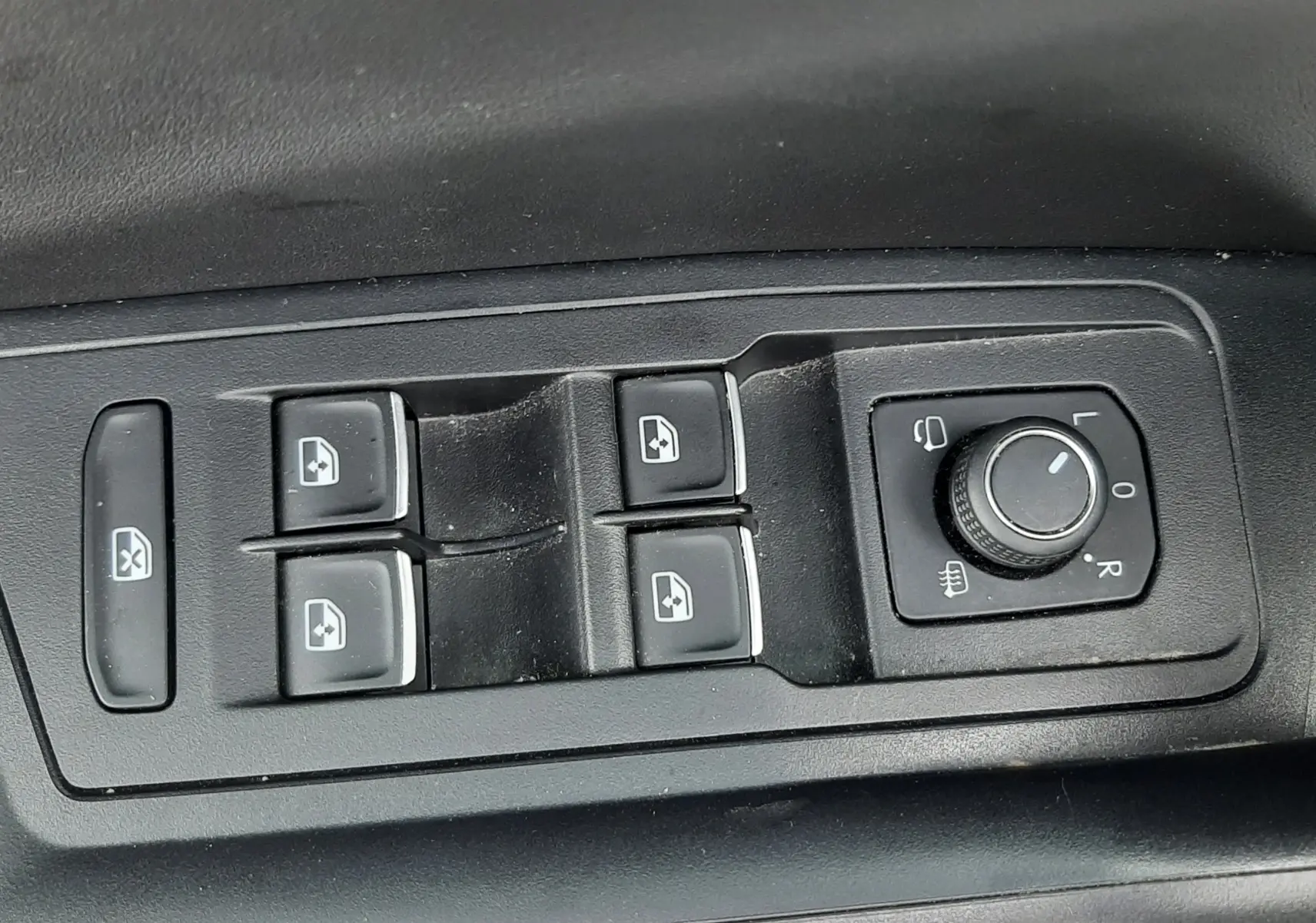 Gros plan sur les commandes de lève-vitres et réglage des rétroviseurs côté conducteur du Volkswagen T-Roc blanc toit noir.