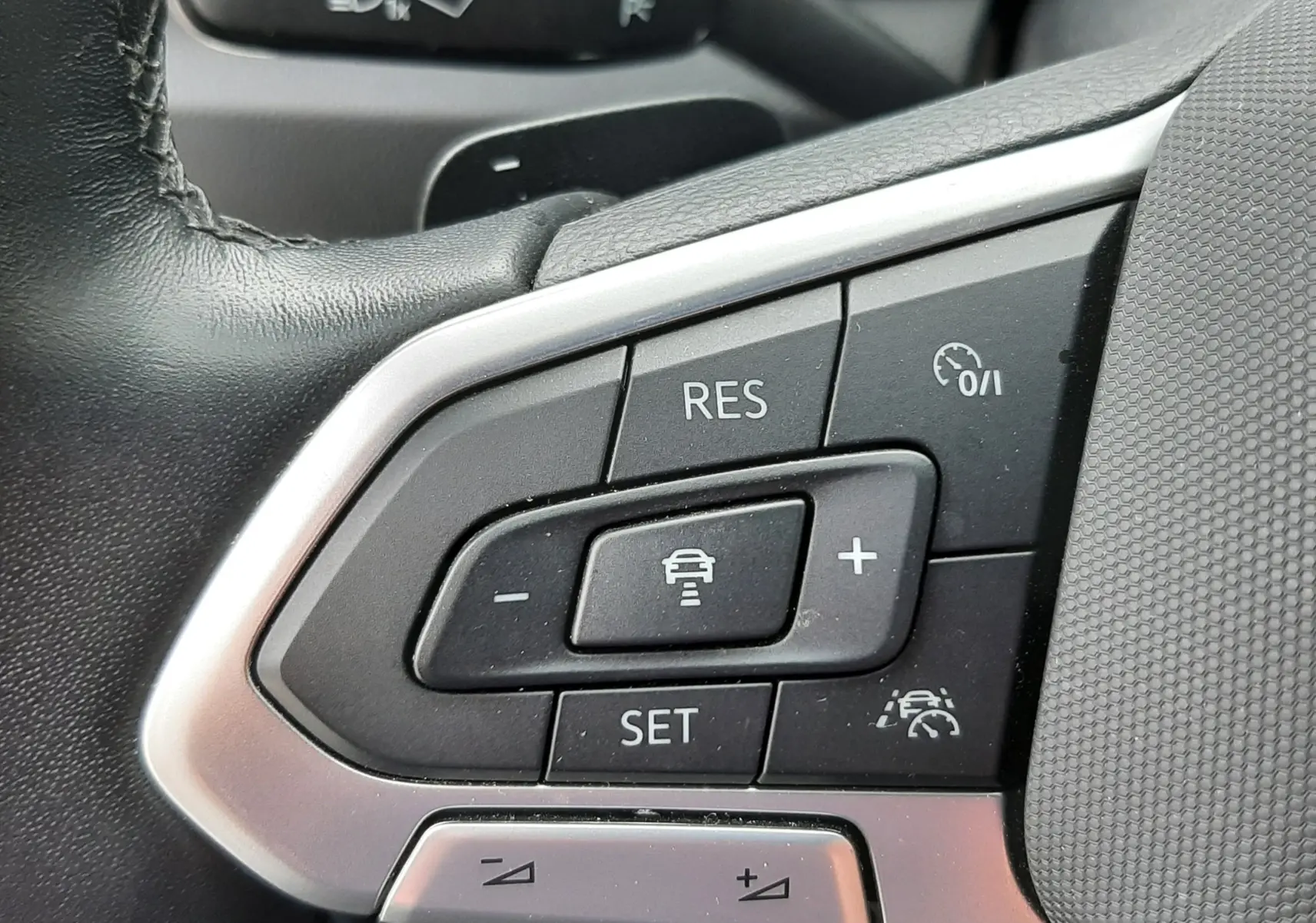 Gros plan sur les commandes de régulateur de vitesse au volant noir du Volkswagen T-Roc 2.0 TDI 2022.