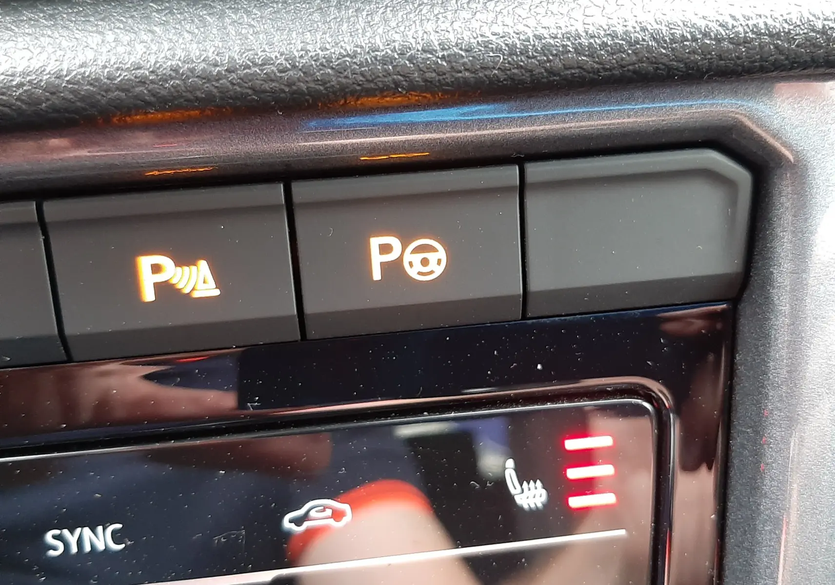 Gros plan sur les commandes de climatisation et assistance au stationnement du Volkswagen T-Roc 2.0 TDI blanc toit noir.