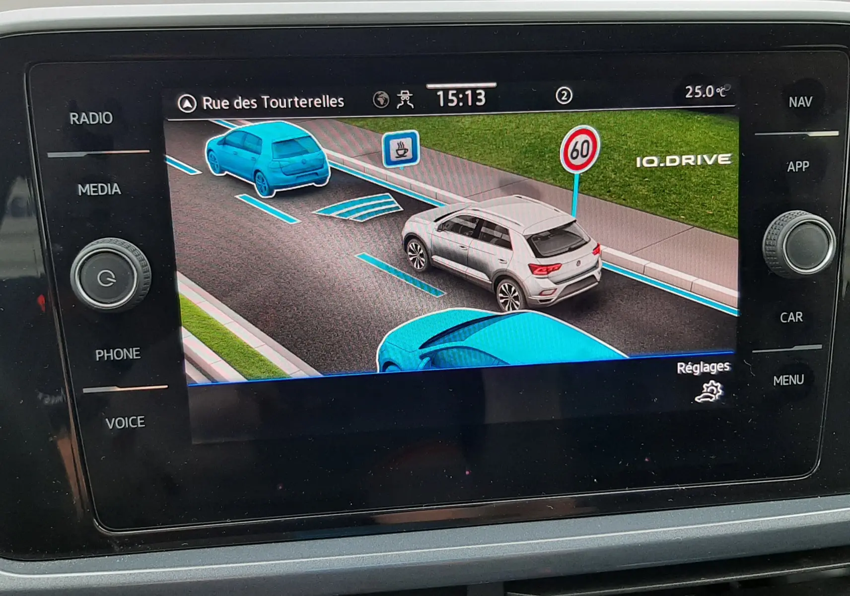 Écran central montrant la navigation 3D avec un Volkswagen T-Roc blanc vu de trois quarts arrière sur route virtuelle.