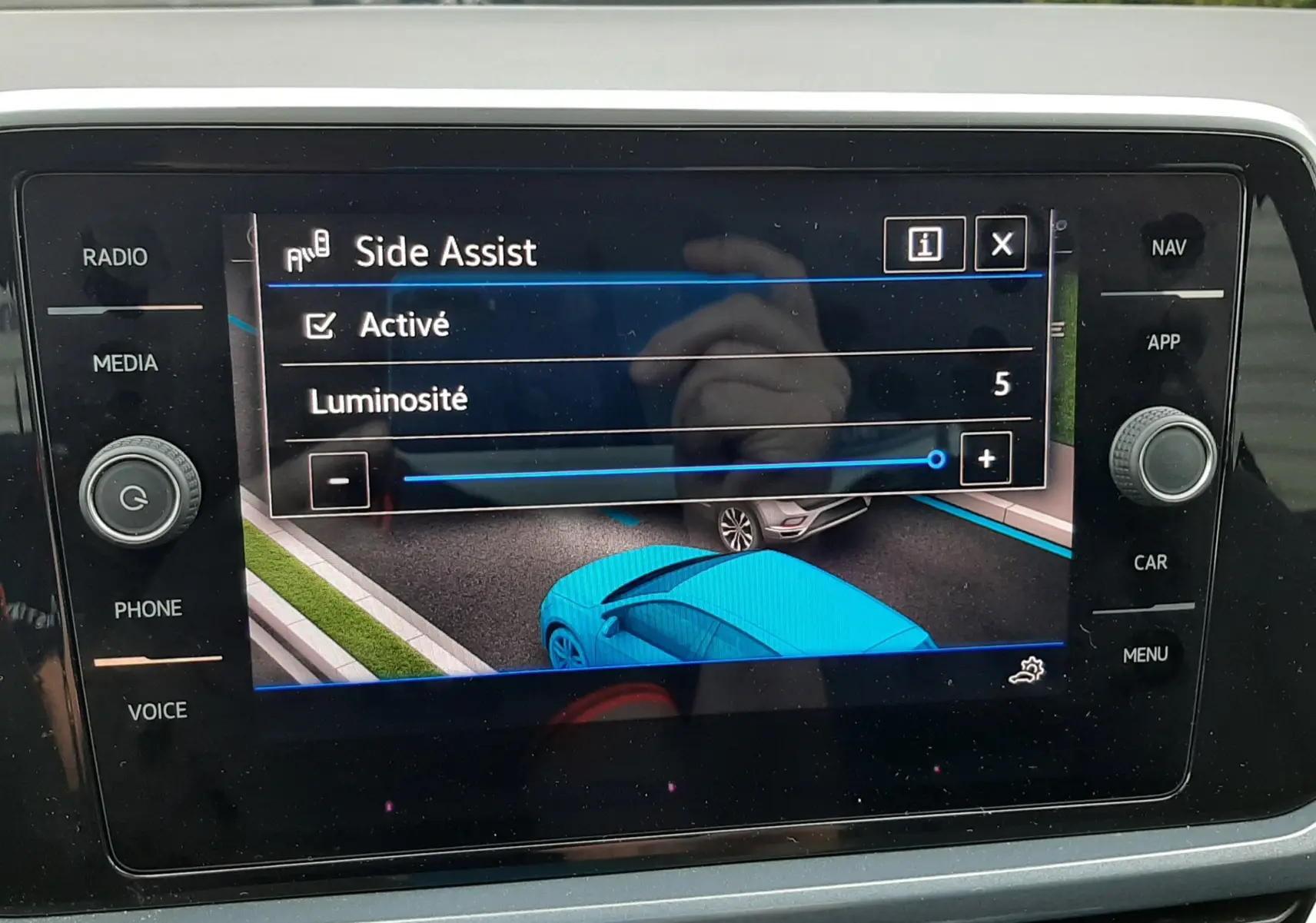 Vue intérieure sur l'écran tactile du Volkswagen T-Roc blanc, affichant l'activation de l'assistance de maintien de voie.