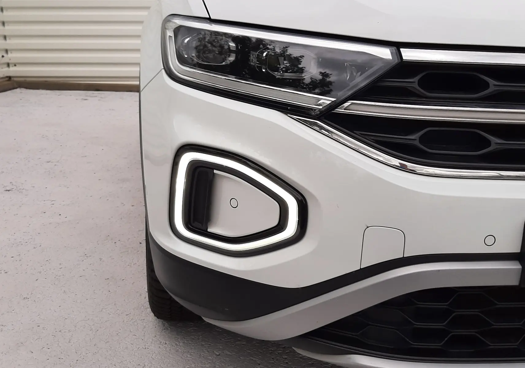 Gros plan sur l'avant gauche du Volkswagen T-Roc blanc pur avec éclairage LED et calandre noire.