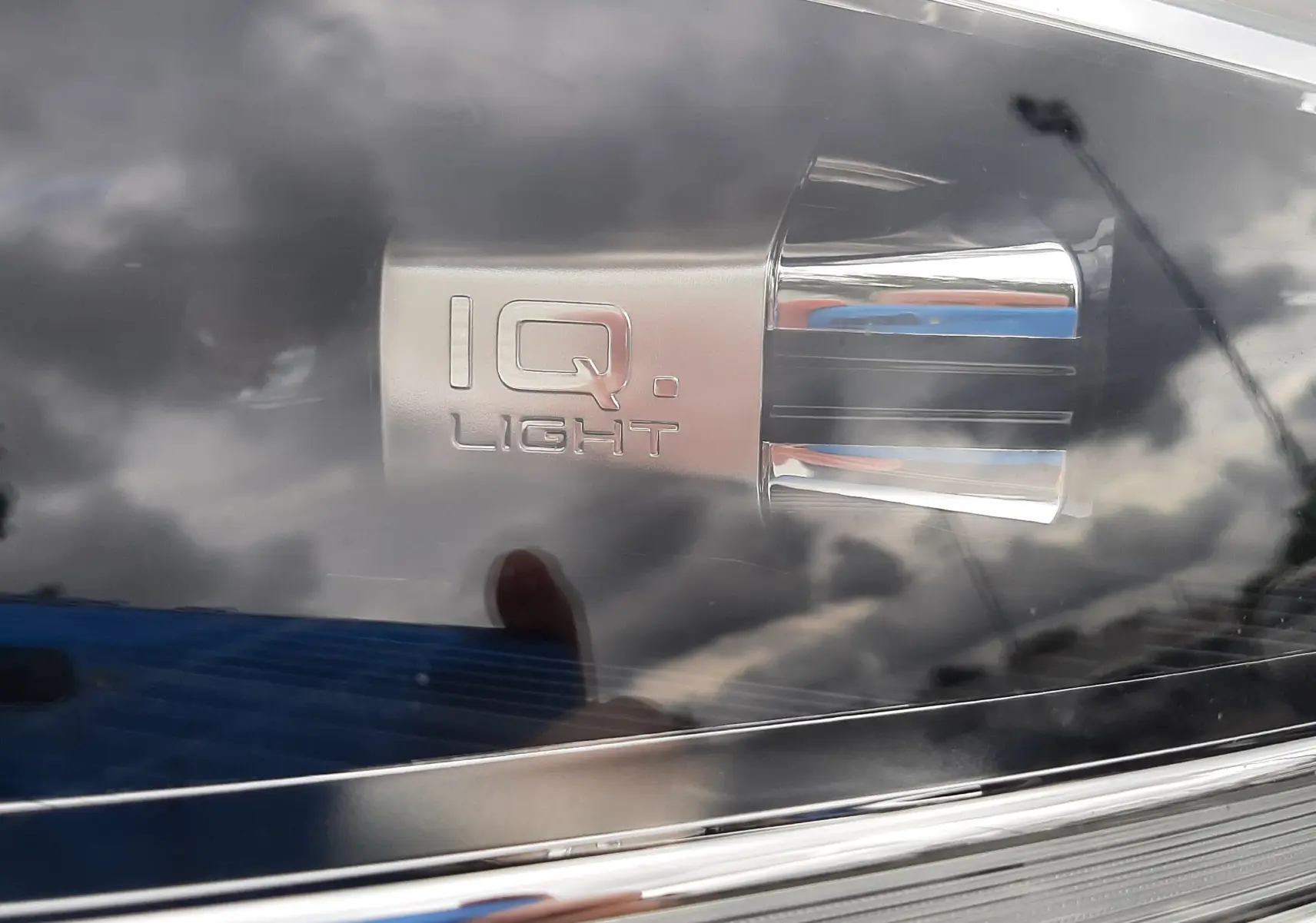 Gros plan sur le phare avant droit du Volkswagen T-Roc blanc pur avec inscription IQ.Light et détails chromés.