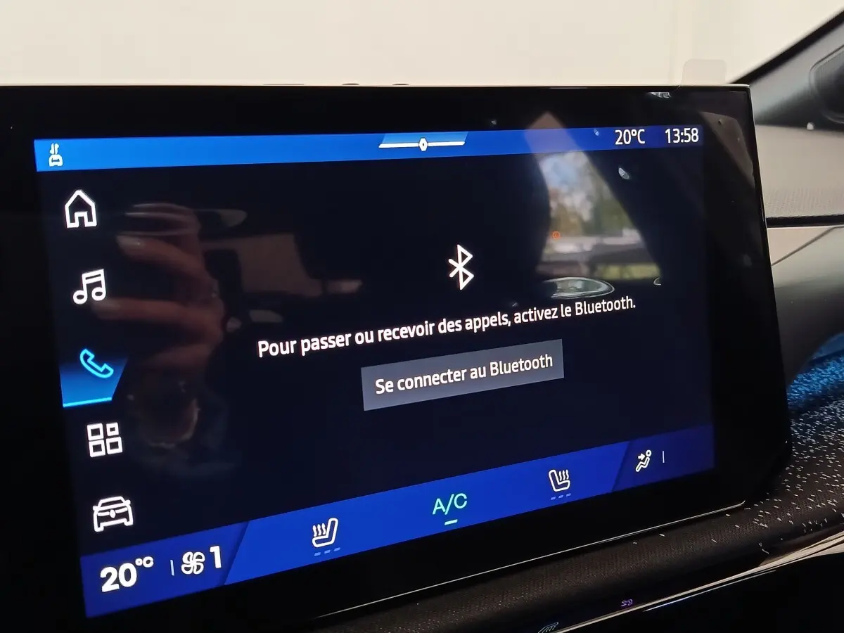 Écran tactile central de la Renault Clio gris foncé, affichage Bluetooth et commandes climatisation visibles.
