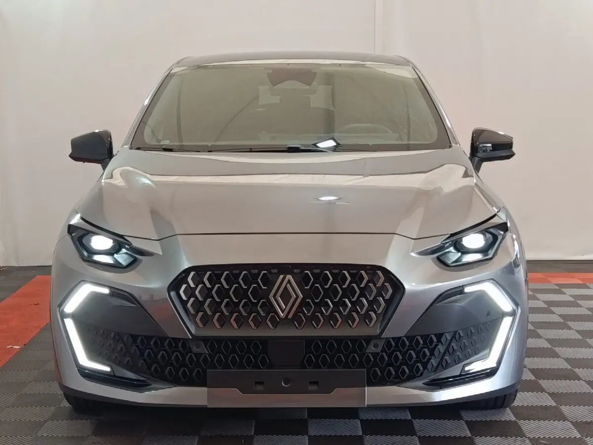 Vue frontale d'une Renault Clio Techno gris foncé avec phares et feux LED allumés, calandre hexagonale distinctive.