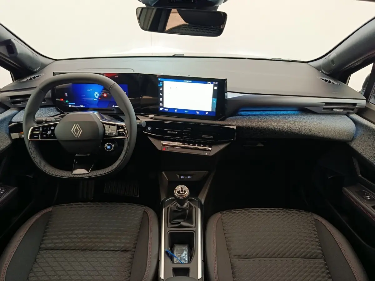 Vue intérieure avant de la Renault Clio Techno TCe 115 gris foncé, tableau de bord moderne avec écran tactile et volant multifonctions.