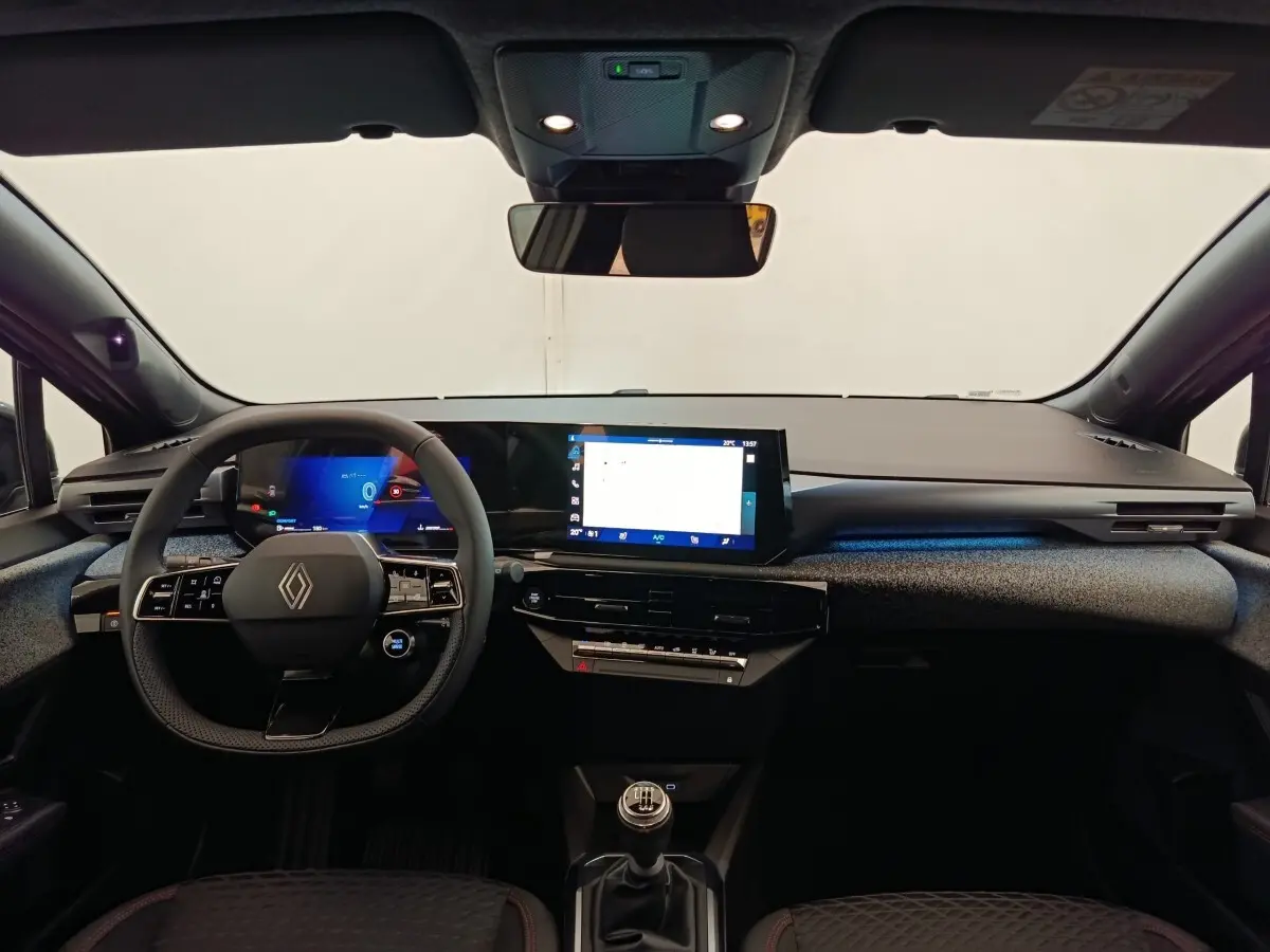 Vue intérieure avant de la Renault Clio techno TCe 115 gris foncé, tableau de bord moderne avec écran tactile et volant multifonctions.