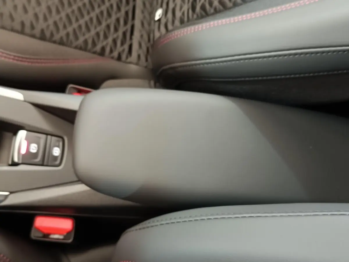 Accoudoir central avant gris foncé avec surpiqûres rouges dans l'habitacle d'une Renault Clio 2026 vue de dessus.